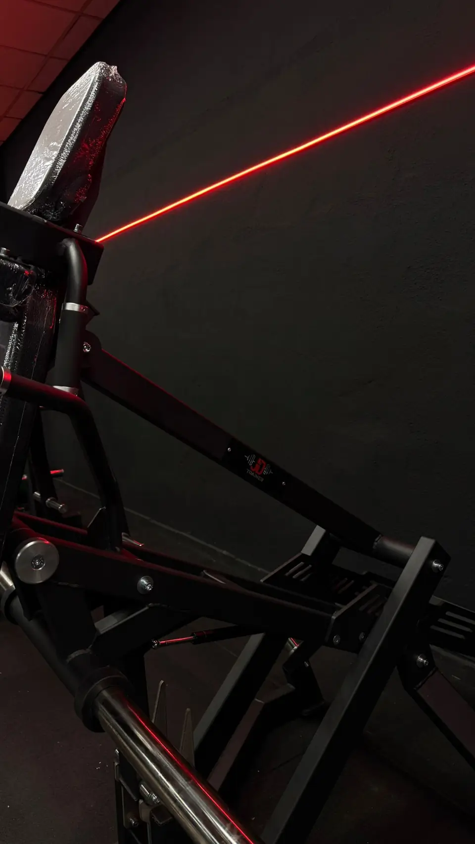 Detalle de una máquina de fuerza junto a la tira de luz LED roja de la pared